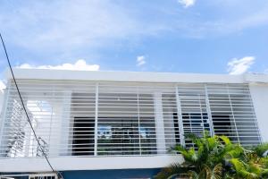 a white building with a large window with blinds at La Villa Salma in Santa Bárbara de Samaná