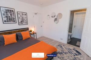 a bedroom with an orange bed and a bathroom at Award-Winning Four Bedrooms House, Parking, WiFi By Derby Short Term Rental Short Lets & Serviced Accommodation Derby in Derby