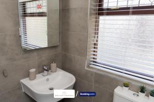a bathroom with a white sink and a mirror at Award-Winning Four Bedrooms House, Parking, WiFi By Derby Short Term Rental Short Lets & Serviced Accommodation Derby in Derby +28 photos