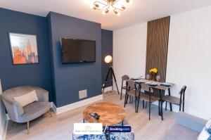 a living room with a table and a tv on a wall at Award-Winning Four Bedrooms House, Parking, WiFi By Derby Short Term Rental Short Lets & Serviced Accommodation Derby in Derby