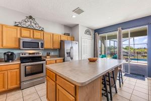 a kitchen with wooden cabinets and a island with a counter top at 7BDM Prvt Pool Villa - Gated Resort 10min to Disney in Kissimmee
