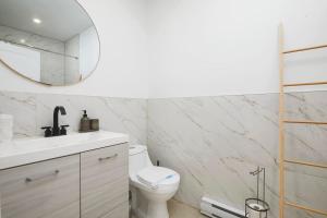 a white bathroom with a toilet and a mirror at Contemporary 2BR Retreat in MTL Village in Montréal
