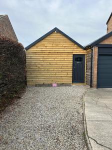 a wooden garage with a door and a driveway at Aiskew Villa Annex in Bedale
