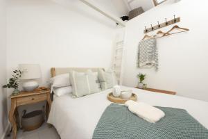 a white bedroom with a bed with a green blanket at 8 Millpool in Mousehole