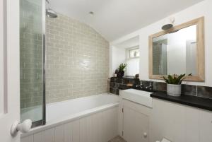 a bathroom with a tub and a sink and a mirror at 8 Millpool in Mousehole +25 photos