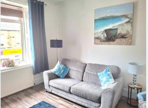 a living room with a couch and a picture of the ocean at Sea Thrift Nook Amble in Amble