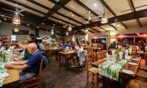 a group of people sitting at tables in a restaurant at Ibis 1 in Cape St Francis Resort in Cape St Francis
