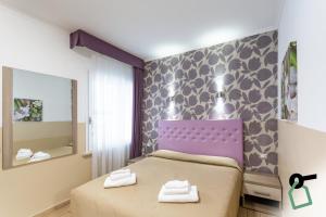 1 dormitorio con cama morada y espejo en HOTIDAY Room Collection - Roma Barberini, en Roma