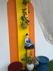 a buddha statue sitting on a stool next to plants at California Nest in Tezpur