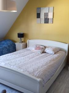 a white bed with two pillows on it in a room at chambres d'hotes et meublés les Hortensias in Lillers