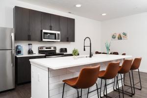 a kitchen with a white counter and brown chairs at Grandeur Unit Royal 103 in Whitestown