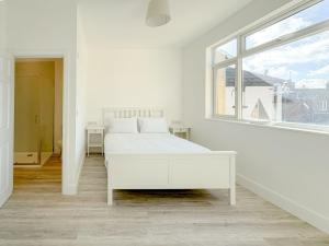 a white bedroom with a white bed and a window at Nelson Road - 3 Bed Terrace in Yarmouth in Great Yarmouth +2 photos