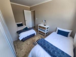 a small bedroom with two beds and a night stand at Leisure Lagoon View Langebaan in Langebaan +15 photos