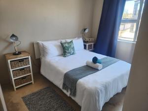a bedroom with a bed with a teddy bear on it at Leisure Lagoon View Langebaan in Langebaan