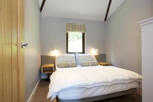 a bedroom with a bed with white sheets and a window at Loch Tay Highland Escapes in Morenish