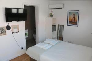 a white room with a bed and a flat screen tv at 9 min Metro to Downtown -Remote working - Free Parking in Porto