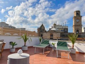 a rooftop patio with chairs and a clock tower at Terrazza De Palma, Vista e Relax in Monopoli