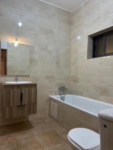 a bathroom with a tub and a toilet and a sink at Villa moderne Lawsmat in Lomé