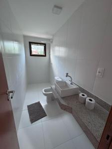 a white bathroom with a sink and a toilet at Residencial Ravena Arraial d'ajuda Casa 7 in Arraial d'Ajuda