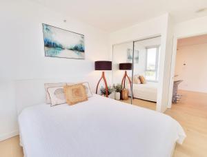a white bedroom with a bed and a mirror at Beautiful 1 BR in the Heart of Downtown: Parking, Pool & Gym in Vancouver +25 photos