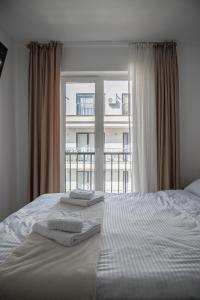 a white bed with two towels on it in front of a window at NexuS Apartments in Sibiu