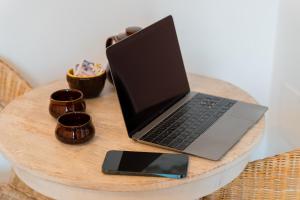 un computer portatile e un telefono cellulare su un tavolo di legno di Dimora Tizzi - Boutique Apartment - By Just Houses SRL ad Alessano