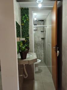 a bathroom with a toilet and a sink with plants at Hostel itabirito in Itabirito