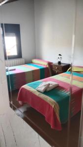 1 Schlafzimmer mit 2 Betten mit bunter Bettwäsche und einem Tisch in der Unterkunft Casa Rural Cuatro Vientos in Santiago-Pontones
