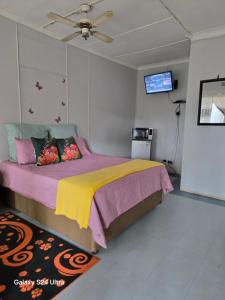 a bedroom with a bed with a yellow and purple blanket at New Dreamland Guesthouse in Mahikeng