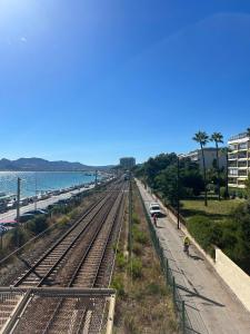 een treinspoor naast de oceaan met een persoon op een fiets bij Studio Moderne Cannes - Parking - Proche de la plage in Cannes +6 foto's