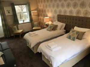 a bedroom with two beds and a chair at The Anchor Inn in Garelochhead