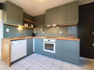 a kitchen with blue cabinets and white appliances at Kind -& diervriendelijk huisje in De Panne +14 photos