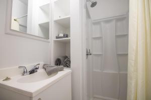 a white bathroom with a sink and a shower at Appartements-Hôtel les Mouettes in Sept-Îles