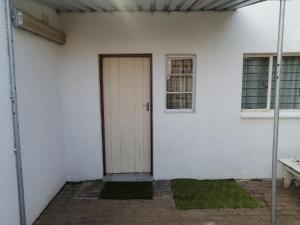 a white building with a door and a window at TRAVELASPA Guest House in Roodepoort