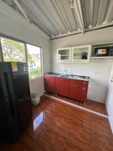 cocina con armarios rojos y lavabo en una habitación en Apartamento Cerca Aeropuerto, en Cali