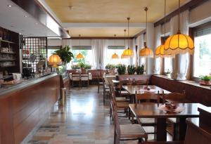 a restaurant with wooden tables and chairs and windows at Albergo Ristorante Cima I Pra' in Ponte nellʼAlpi