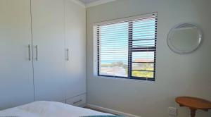 a bedroom with a window with a mirror and a bed at Vooruitzicht in Gansbaai