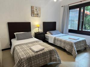 deux lits dans une chambre avec une fenêtre dans l'établissement Casa en Carilo con Pileta, Quincho y Parque Cercado para 8 Personas, à Carilo