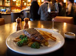 a plate of steak and vegetables with a glass of wine at InterContinental New York Times Square by IHG in New York
