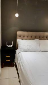 a bedroom with a white bed with a black night stand and a lamp at Prestige Loft in Contagem +19 photos