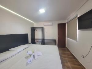 a bedroom with a large white bed with towels on it at Hotel Sea Angels in Arraial do Cabo
