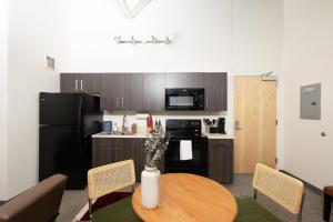 a kitchen with a table and a kitchen with a black refrigerator at Cream City 2BR Apt - Just 3 Blocks to Fiserv with Gym and Parking in Milwaukee