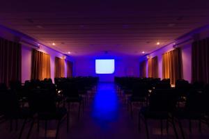 a room with chairs and a screen with purple lights at Sagrados Corações - Pousada in Pindamonhangaba