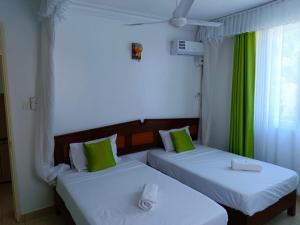 two beds with green pillows in a room at Noni's Place, Greenwood Gardens, Mtwapa in Mtwapa +31 photos