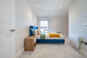 Un dormitorio con una cama azul y una ventana. en ZAI Stays- LutonTown NEWModern 2bed flat, en Luton