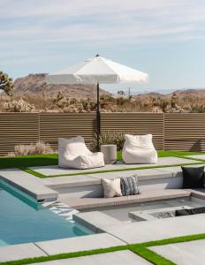 a swimming pool with pillows and an umbrella next to a swimming pool at Ventana Cove Pickleball Retreat in Yucca Valley