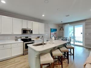 een keuken met witte kasten en een keukeneiland met barkrukken bij Cottages at Old Bay #5 in Orange Beach