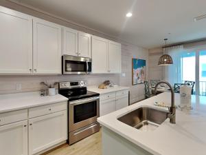 een keuken met witte kasten en een roestvrijstalen wastafel bij Cottages at Old Bay #5 in Orange Beach