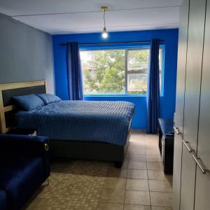 una camera da letto blu con un letto e una finestra di Greggs Place at Capital Hill Arcadia a Pretoria Altre 21 foto