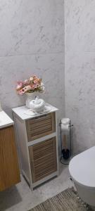 Un baño con inodoro y un jarrón de flores sobre un mostrador. en White Design Apartment, en Aveiro